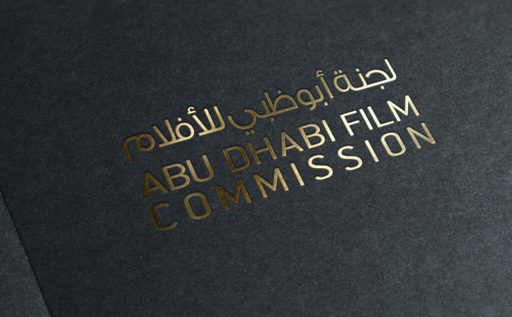 Abu Dhabi Film Commission logo engraved against a black background.